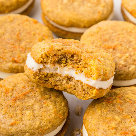 Carrot Cake Oatmeal Cream Pies stacked with one bitten