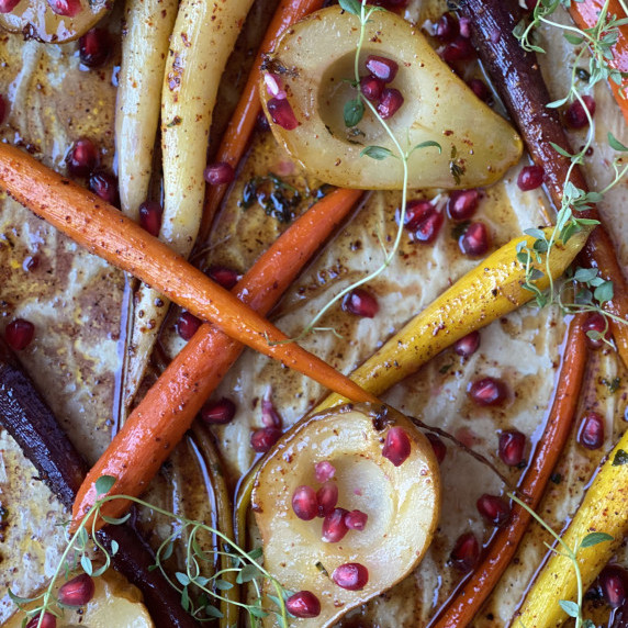 Bourbon glazed rainbow carrots and pears with pomegranite and thyme on parchment.