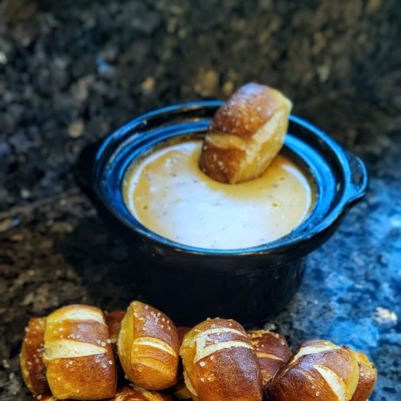 pretzel bites arranged in front of a small crockpot with melted cheese dip