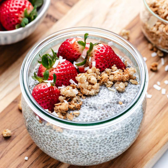 Chia pudding in a glass jar with strawberries and granola on top.