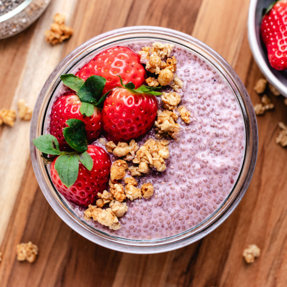 Strawberry chia seed pudding in a glass jar with granola and sliced strawberries.