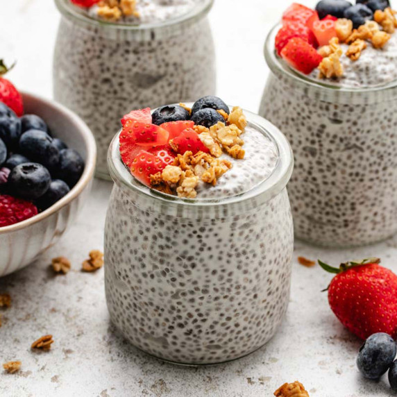 Yogurt chia seed pudding in a jar with diced strawberries, blueberries, and granola on top.