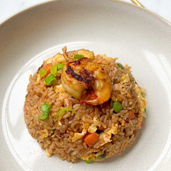 shrimp and chicken fried rice served in a plate with golden chopsticks in the background