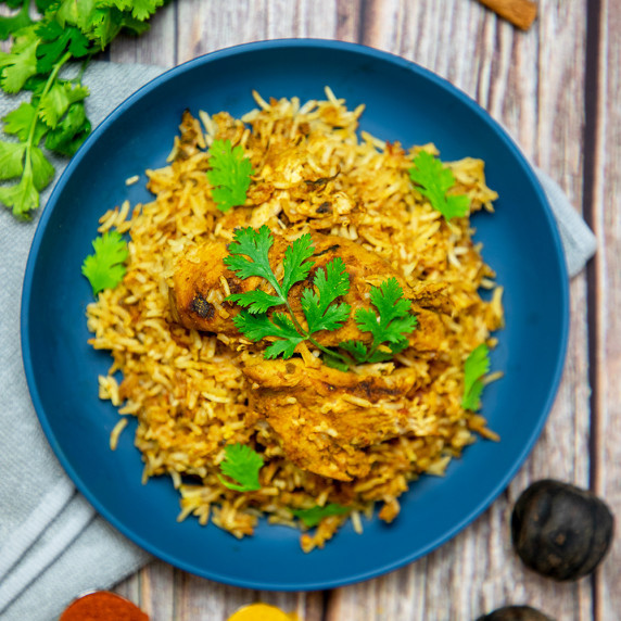 Chicken biryani in a blue bowl topped with coriander. 