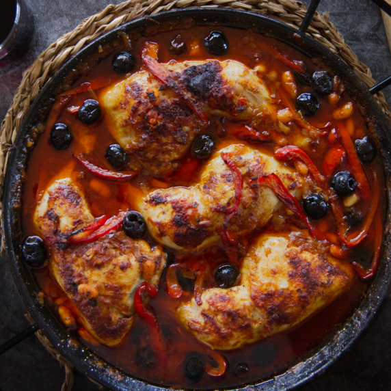 A large pan of Spanish Chicken with a smoky Bravas sauce, topped with black olives.