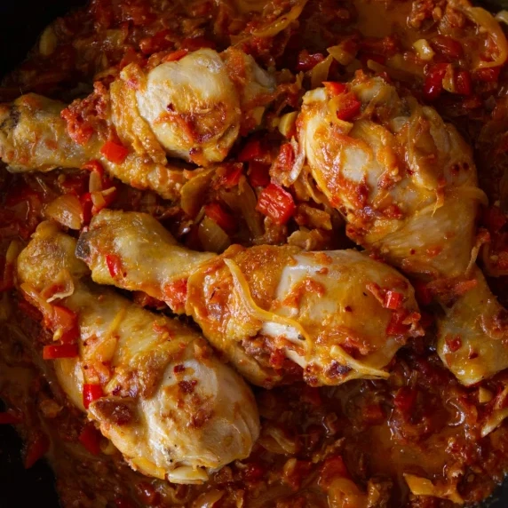 Roasted chicken drumsticks covered in a red pepper and tomato sauce. 