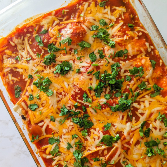 A chicken enchilada casserole topped with sauce, cheese, and fresh cilantro