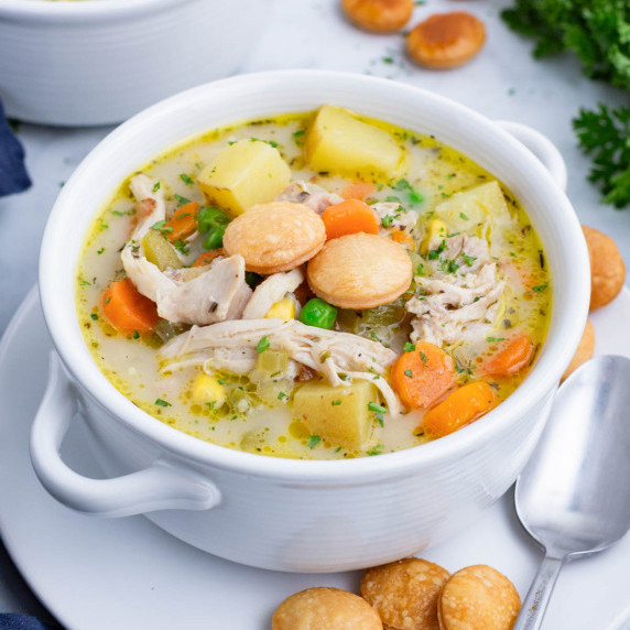 Chicken Pot Pie Soup RECIPE served in a white soup bowl with garnishes. 