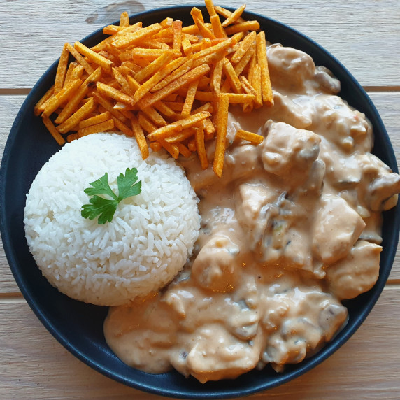 a black plate with rice, chicken stroganoff and potato sticks.