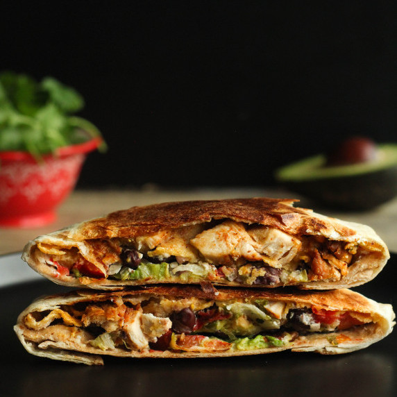 Chicken crunch wrap cut in half and stacked on top of each other with ingredients exposed.