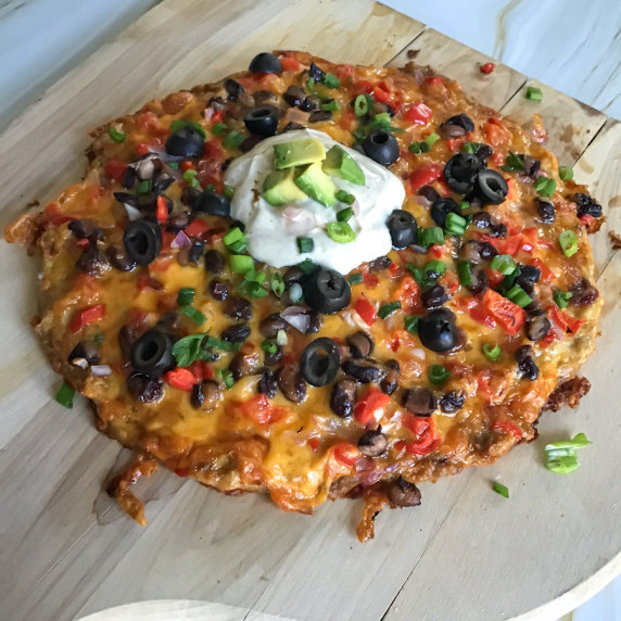 Taco flavored chicken crusted pizza with melted cheese and toppings and chili lime Greek yogurt