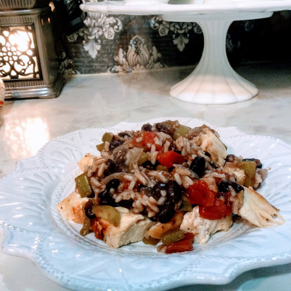 Chicken, black beans, vegetables plated on white scalloped stoneware plate sitting on countertop 