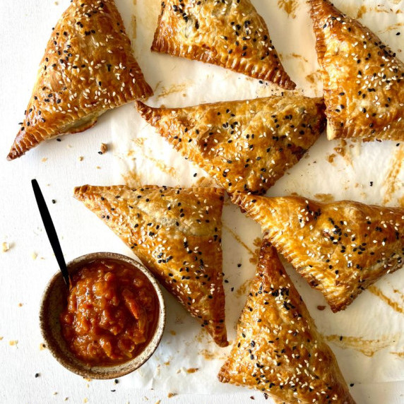 puff pastry triangles on baking paper with bowl of tomato chutney