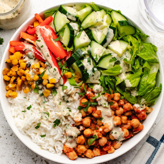 Chickpea bowl with rice, corn, lettuce, cucumber, red bell peppers, and tahini lime dressing.