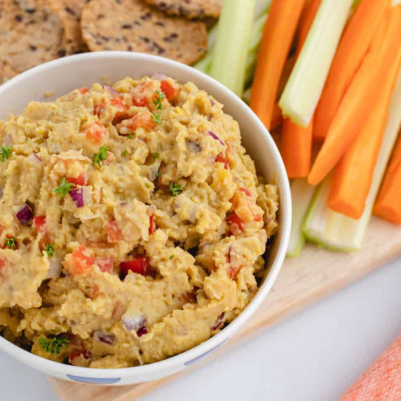 Curry chickpea salad in a bowl with carrots, celery, and crackers.