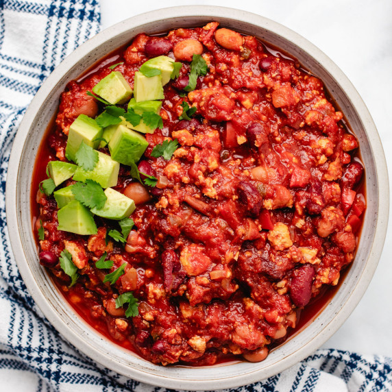 Vegan chili with tofu in a bowl with diced avocado and cilantro.