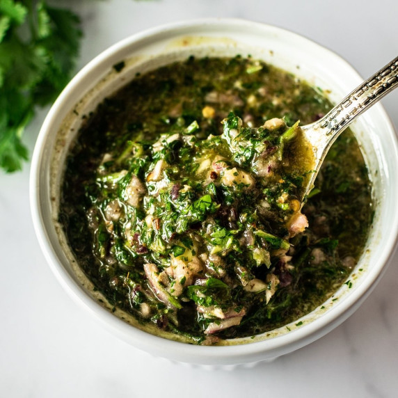 chimichurri sauce in a white bowl with a spoon.