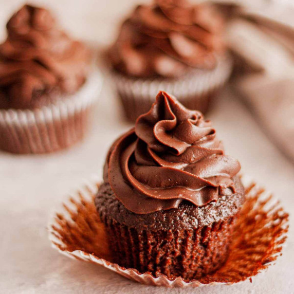 Chocolate cupcakes with cocoa ganache and an open paper liner.