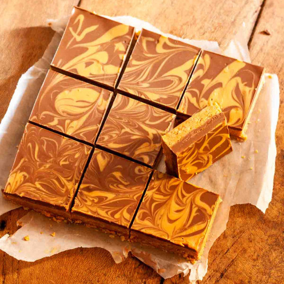 Chocolate peanut butter oatmeal bars cut into squares on parchment paper on a wooden surface.