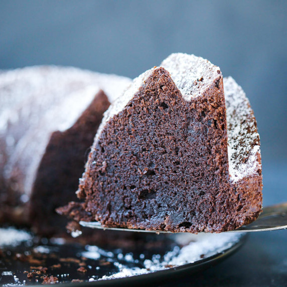 the best chocolate pound cake sliced with whipped cream on black plate