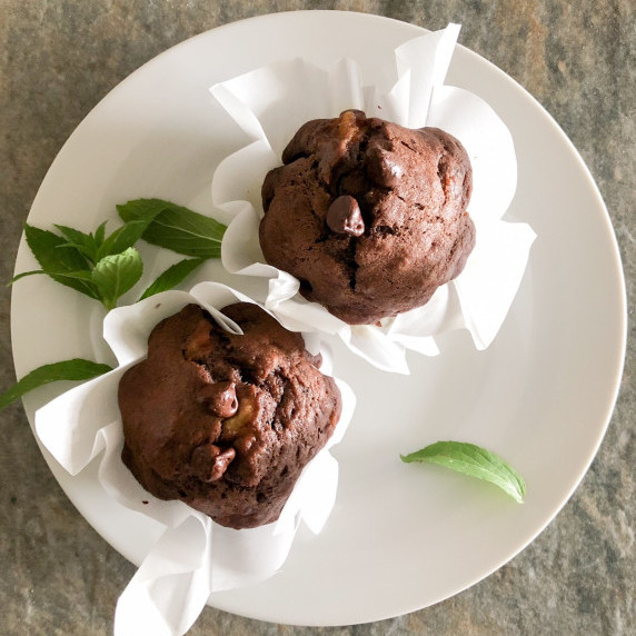 Banana Chocolate Chip Muffins arranged on a white plate with fresh mint leaves for color