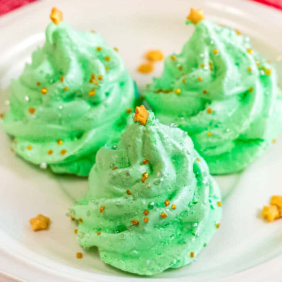 Square image of three green meringue cookies shaped like Christmas trees,