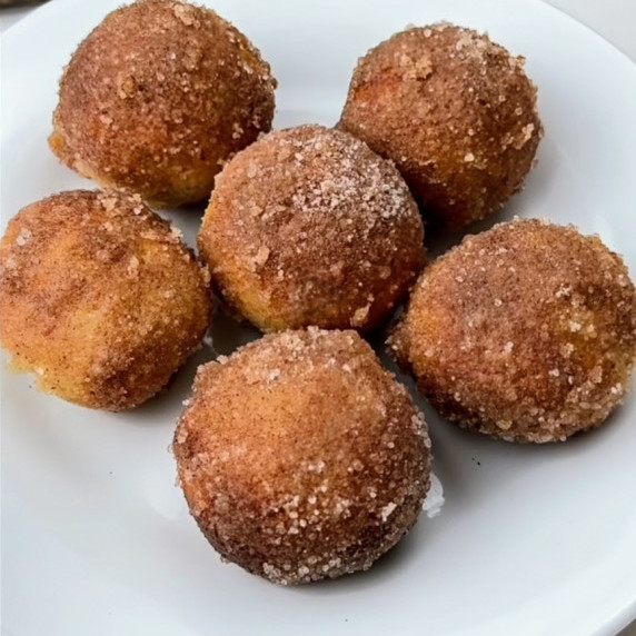 A plate of finished Air Fryer Cinnamon Donut Balls, golden brown and coated with cinnamon sugar.