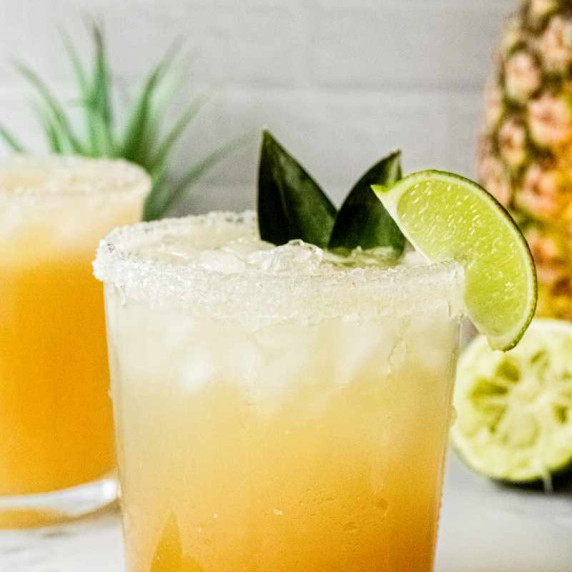 Close up of a golden virgin margarita made with pineapple and lime in a rocks glass rimmed with salt