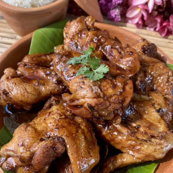 Coca-cola chicken wings with a coriander leaf on top.