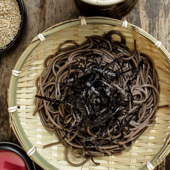Closeup of Japanese cold soba noodles in a bamboo bowl.