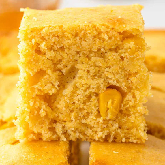 Close up side view of cornbread stacked on other pieces.