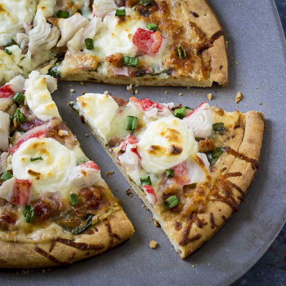 Overhead close up of sliced crab pizza on a metal pan.