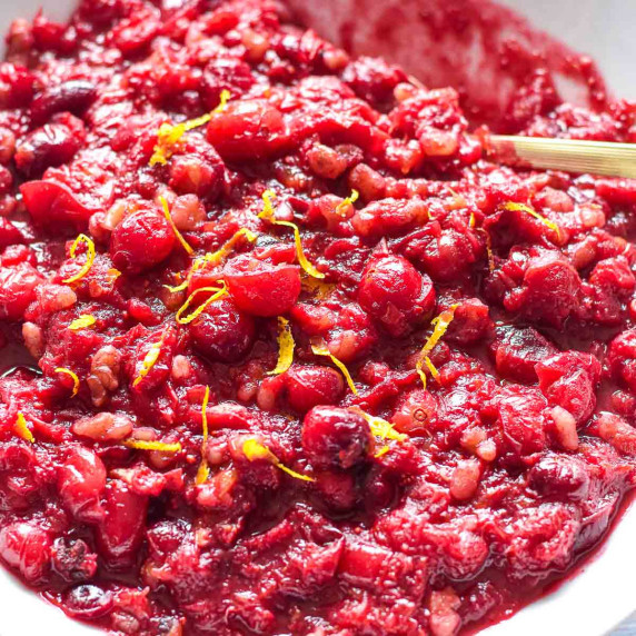 cranberry chutney topped with orange zest in a white bowl with a spoon.