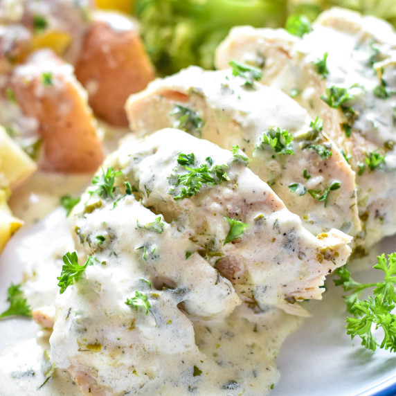 creamy ranch chicken breast sliced and coated with sauce on a plate.