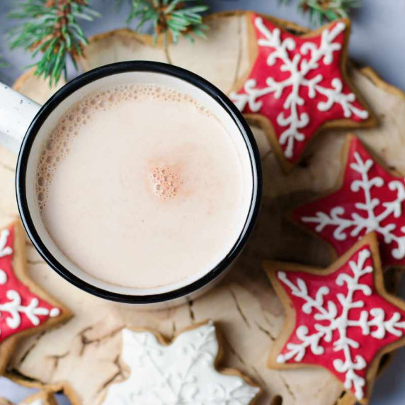 Top view of a mug of cocoa surrounded by sugar cookies.