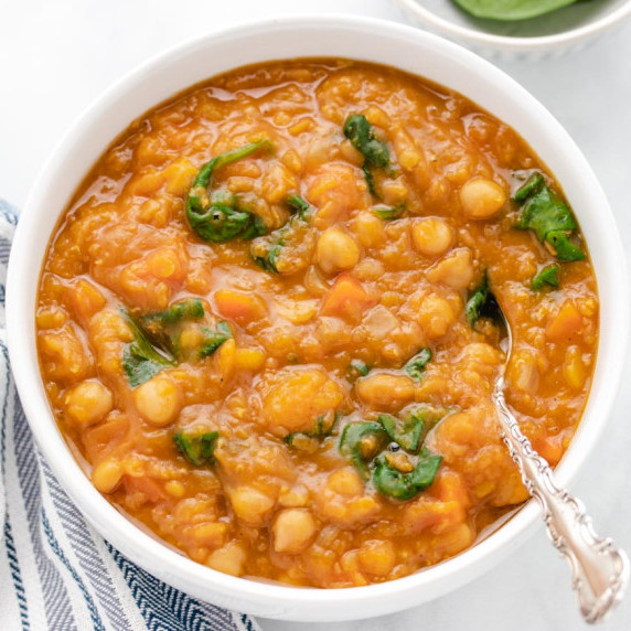 Butternut squash and chickpea curry soup in a bowl with a spoon.