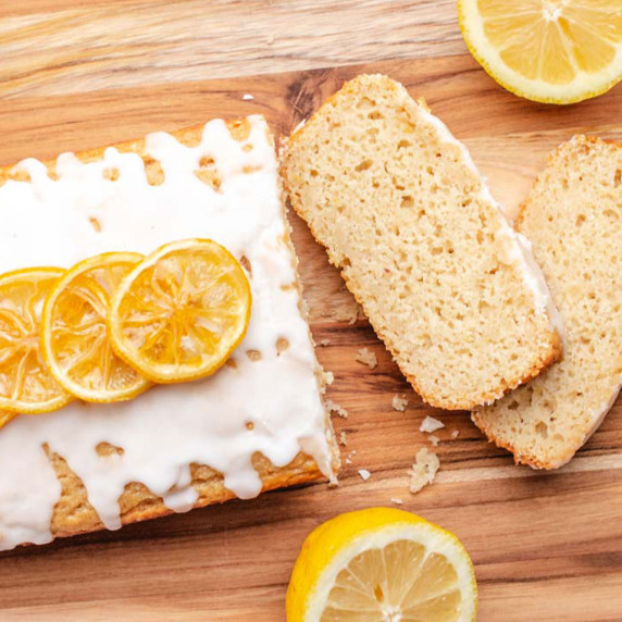 Vegan lemon loaf with icing and candied lemons cut into slices.