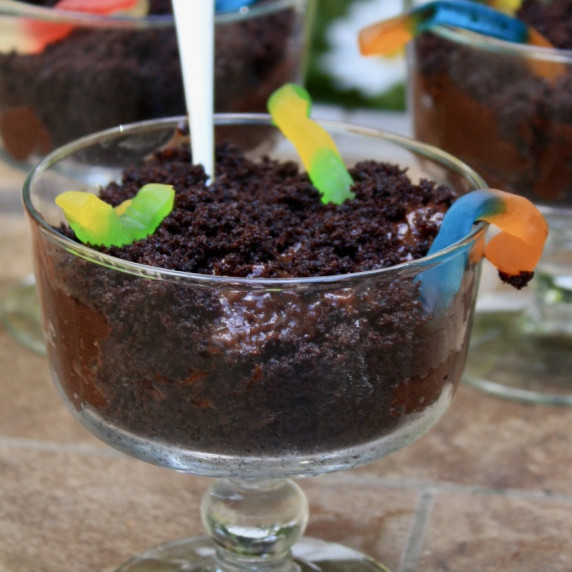 Crumbled cake with chocolate pudding and colorful gummy worms in mini-trifle dishes.  