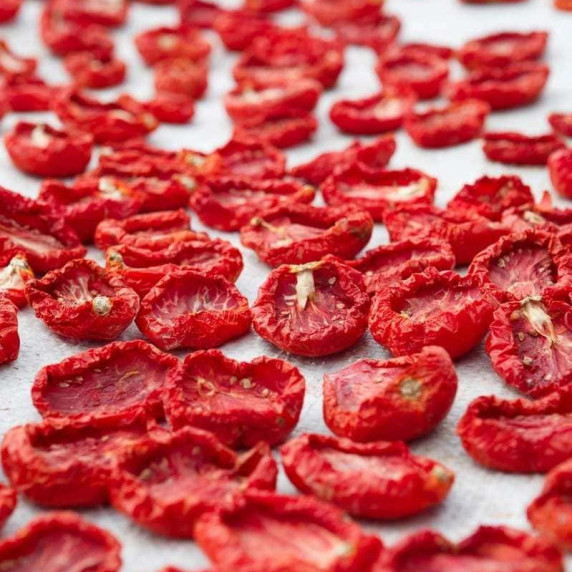 Bright red dehydrated tomatoes in a single layer on parchment paper.