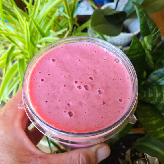A bright pink smoothie against some foliage