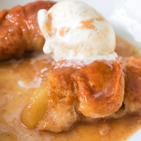 Apple dumplings on a plate with a scoop of vanilla ice cream.