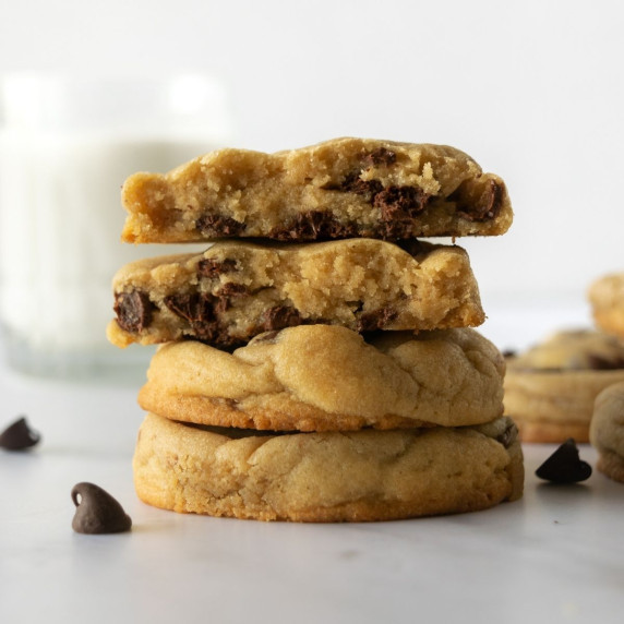 stacked chocolate chip cookies on a white table.