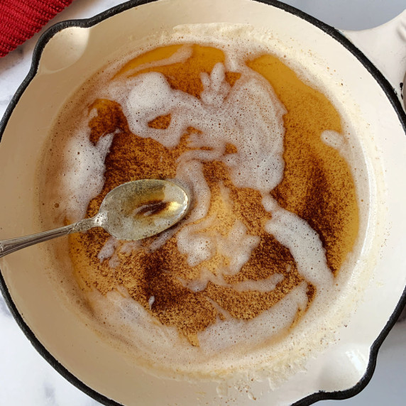A white skillet with browned butter and a spoon.
