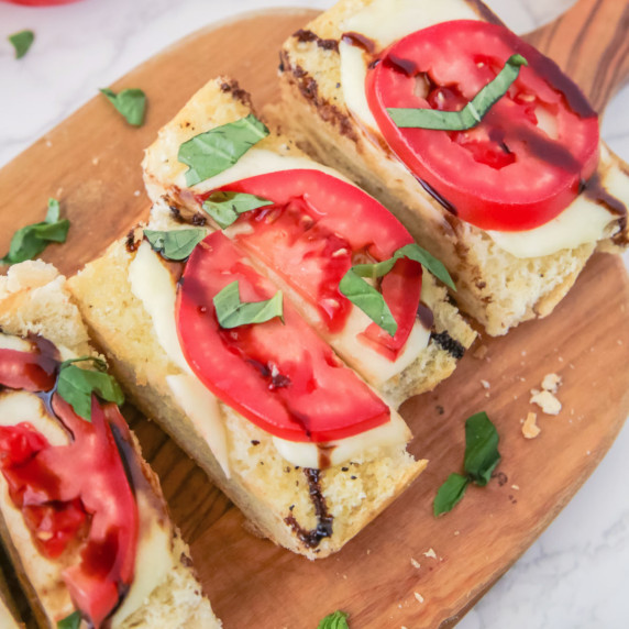 Slices of caprese garlic bread on a cutting board.