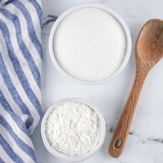 A bowl of granulated sugar and a bowl of powdered sugar.