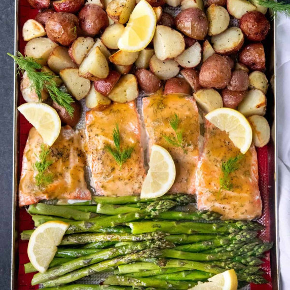 Overhead of sheet pan dinner including maple glazed salmon with roasted asparagus and potatoes.