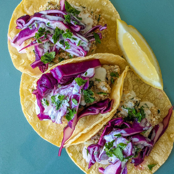 Three fish tacos topped with red cabbage