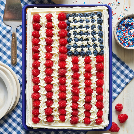 overhead view of a cake decorated like the American flag with blueberries and raspberries