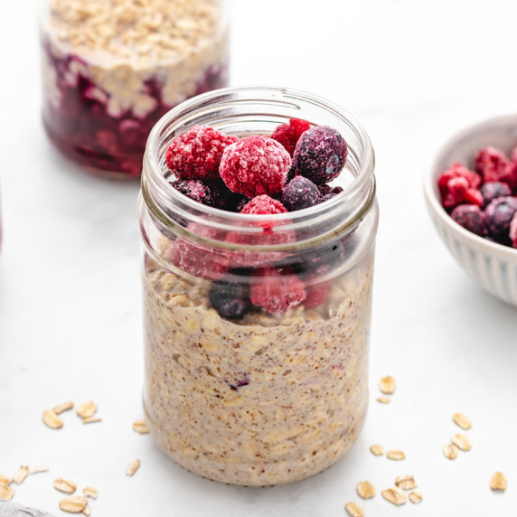 Overnight oats in a jar with frozen berries on top.