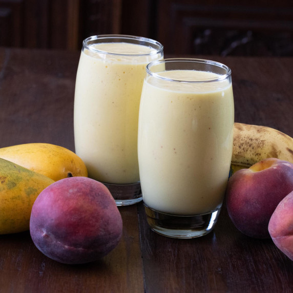 fruit smoothies in glass surrounded by fruits